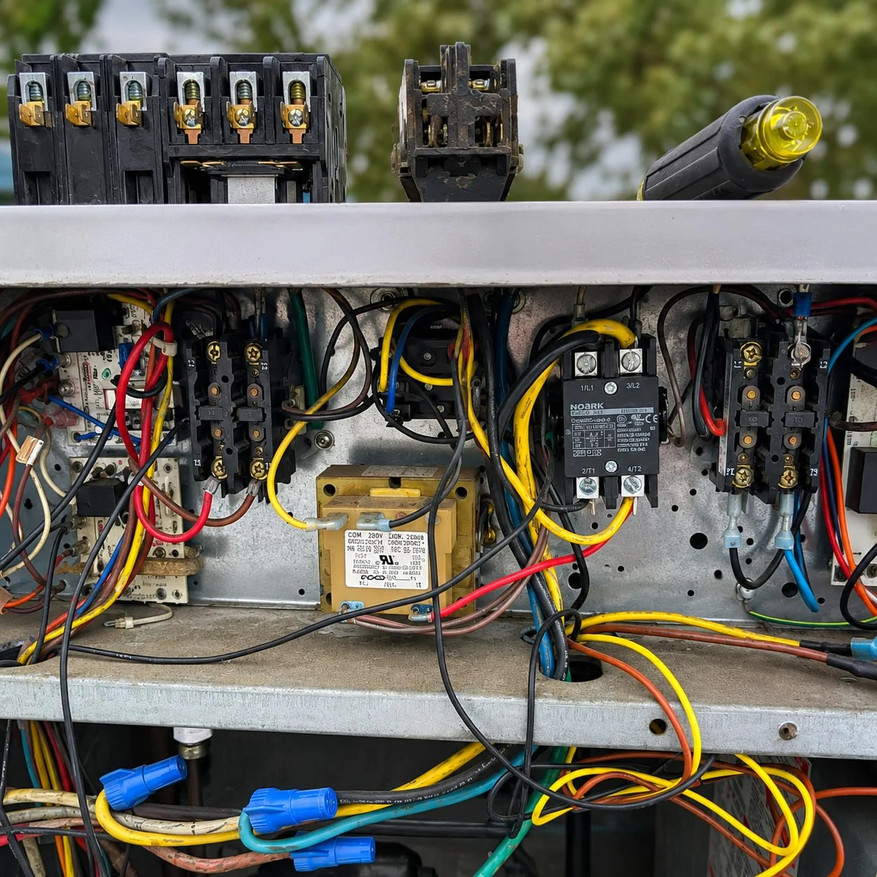 Open HVAC electrical control panel during professional repair with contactors, wiring, and service tools.